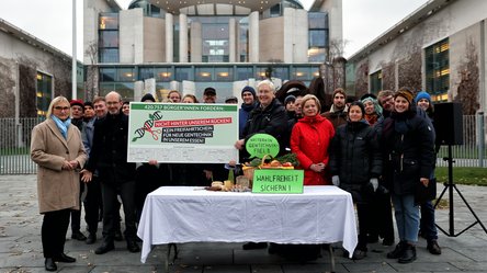 Mehrere Personen stehen vor dem Kanzleramt in Berlin und halten ein Poster hoch